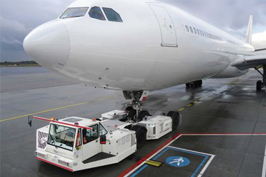 Airport tug pushing airplane on wet tarmac
