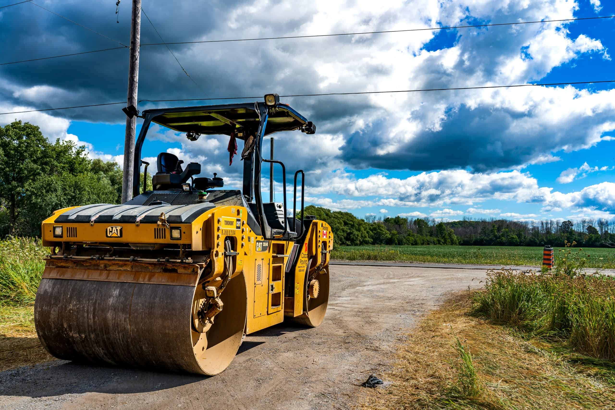 Yellow road roller on rural dirt road
