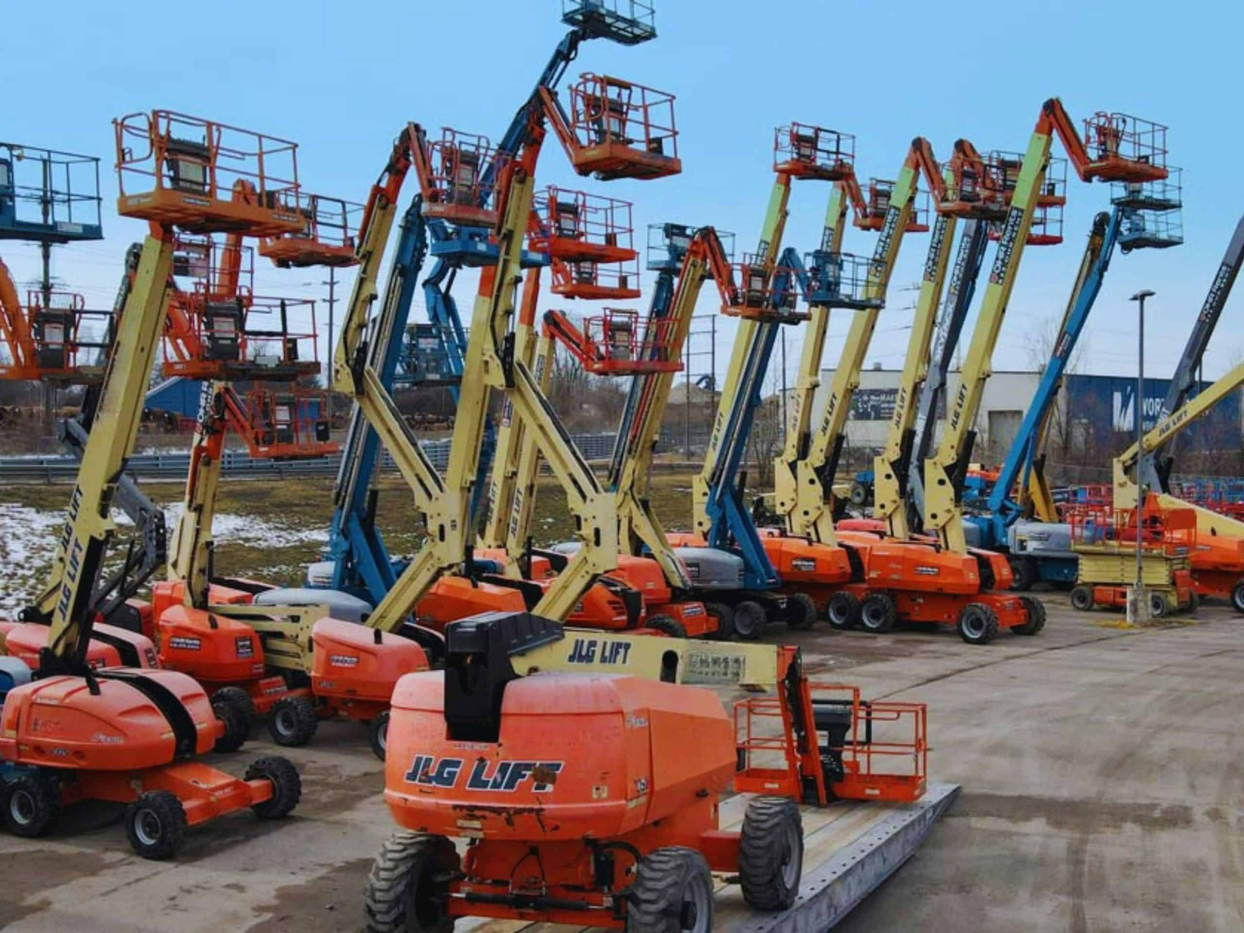 Multiple boom lifts lined up in equipment yard