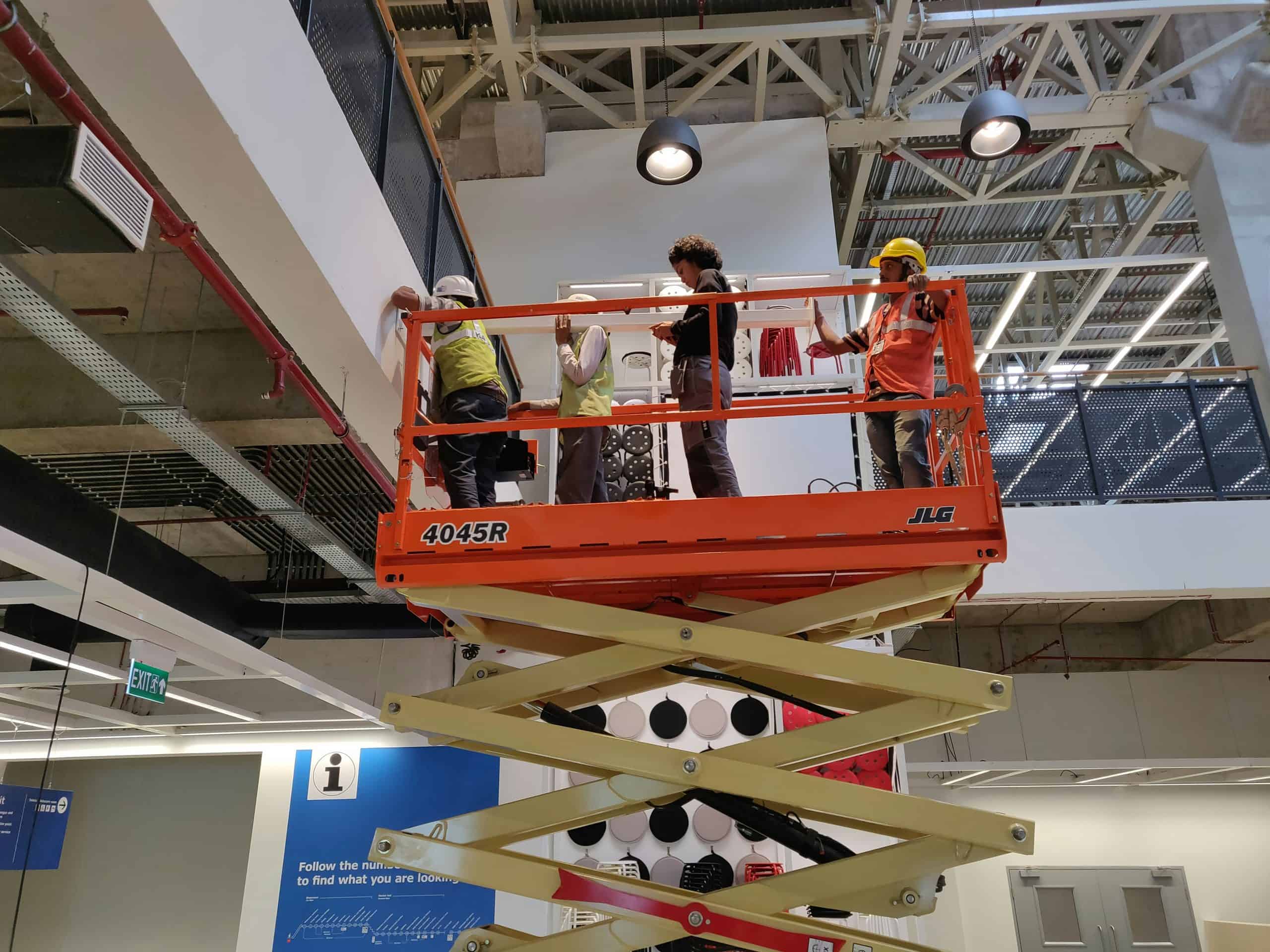 Workers installing ceiling fixture on scissor lift