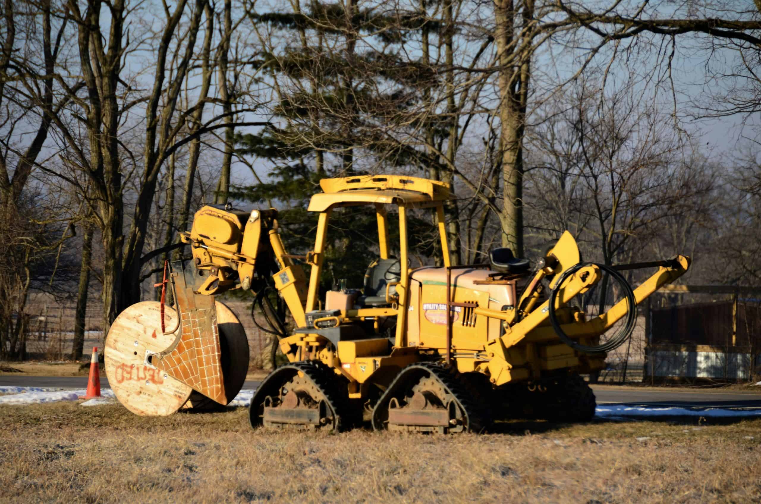 Yellow construction vehicle carrying large wooden cable spool